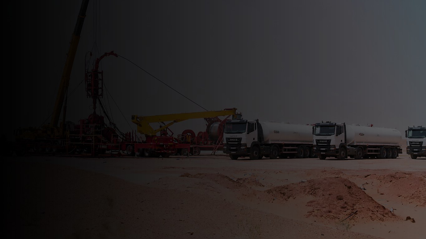 Oil field service site with rig and tanker trucks